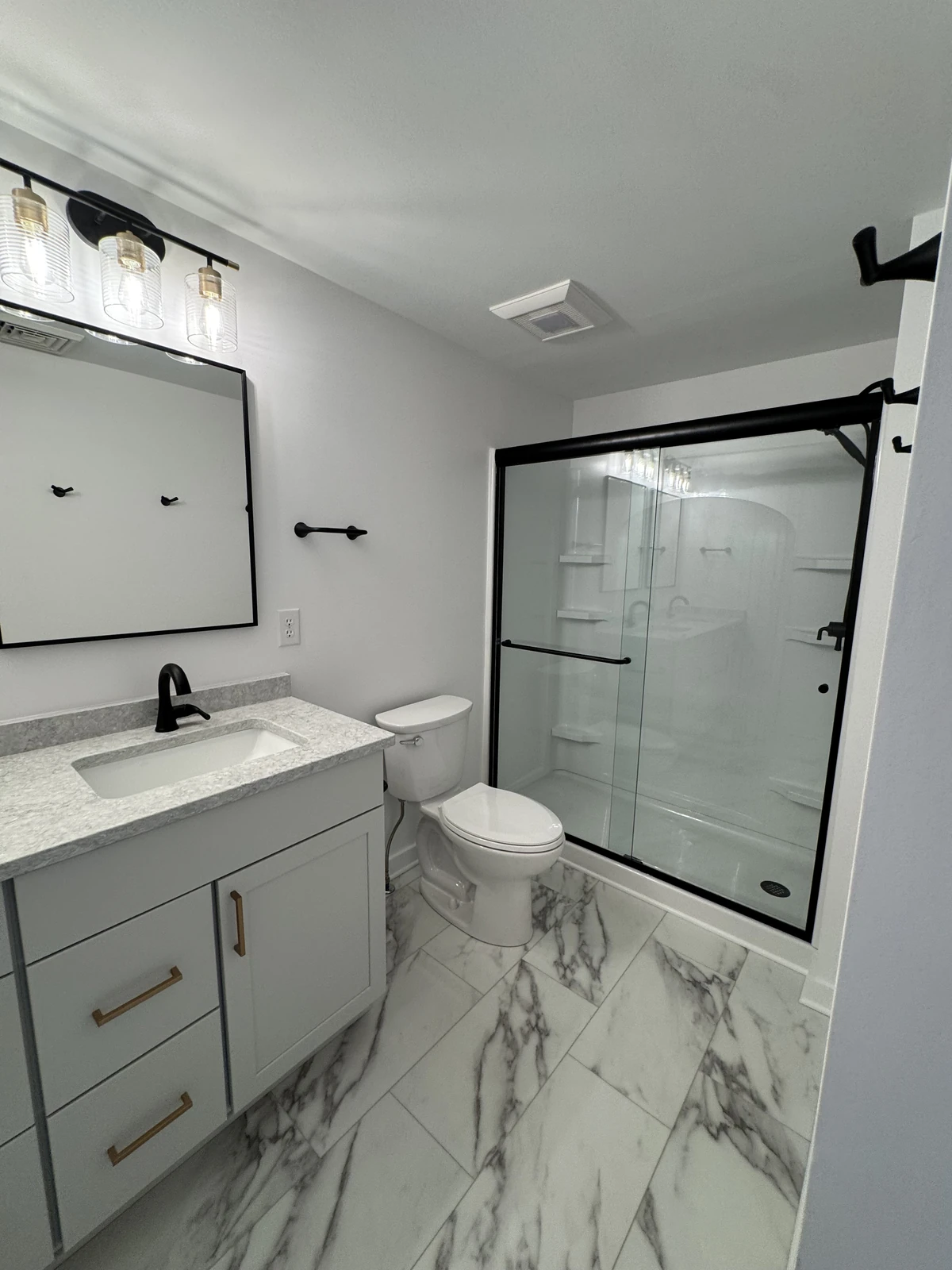 Bathroom with marble floor and black-frame shower