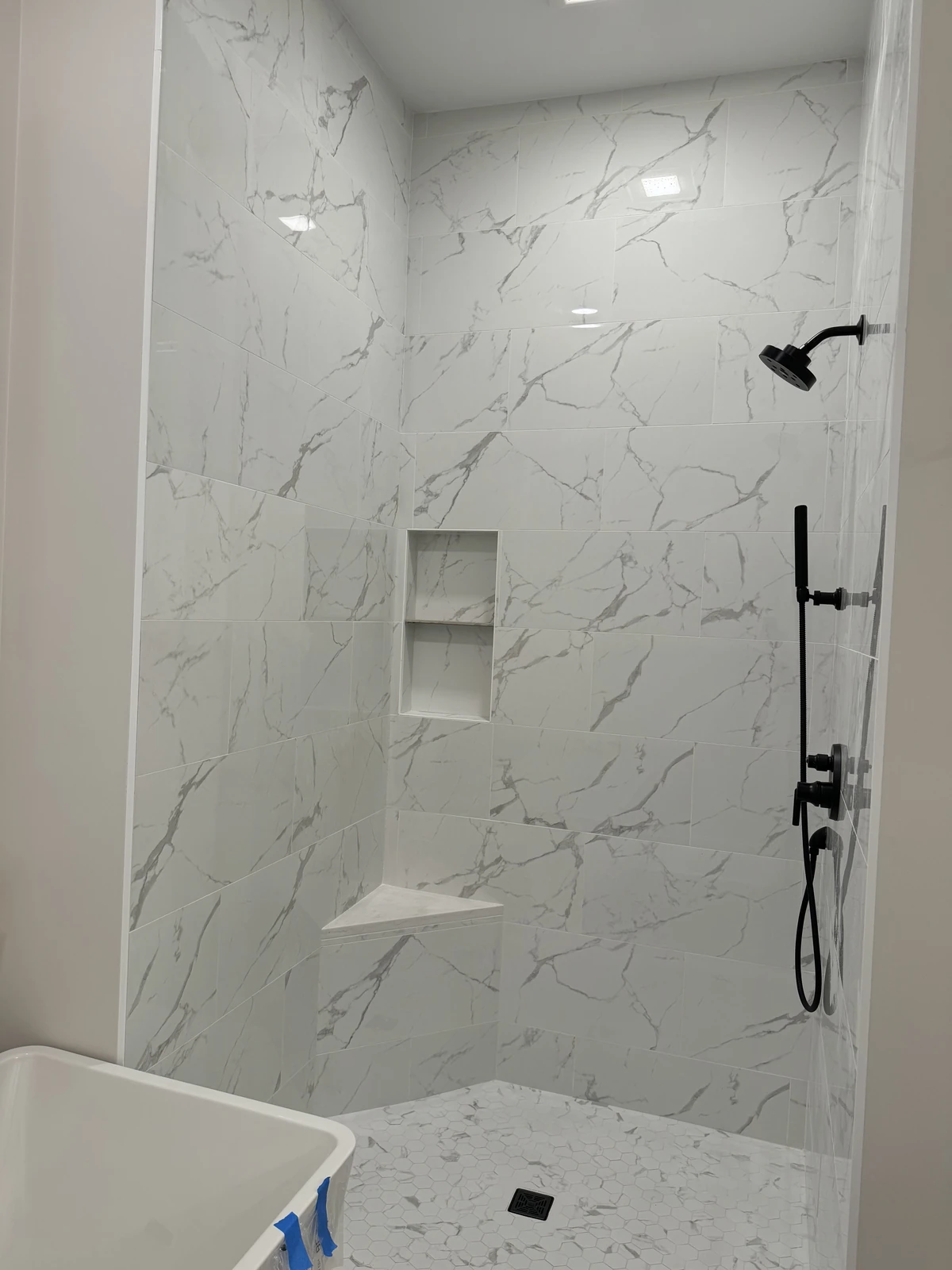 Marble-look tile shower with black fixtures