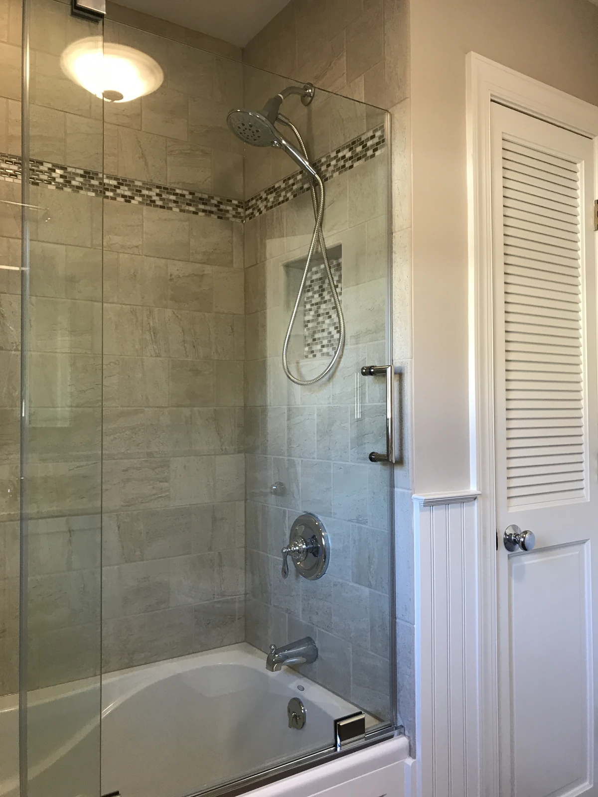 Beige tile tub and shower with mosaic band