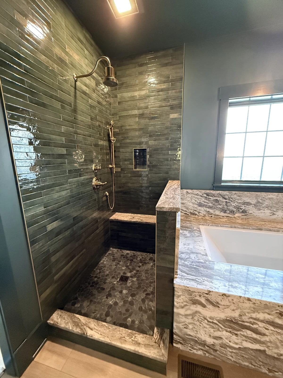 Dark green tile shower with tub deck