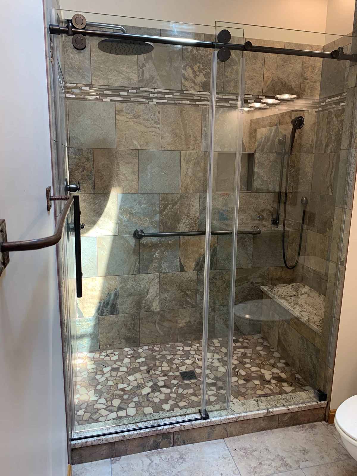 Stone tile shower with sliding glass door